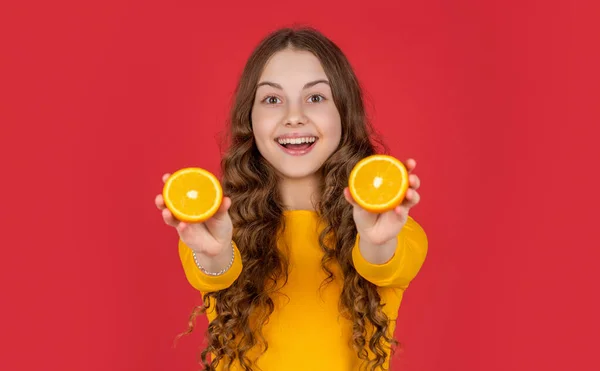 Stock image smiling teen child hold orange fruit on purple background.