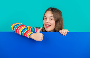 Boş mavi kağıdın arkasında reklam için fotokopi alanı olan mutlu bir çocuk. başparmak yukarı.