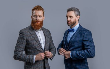 Smokinli karizmatik adamlar stüdyoda. Smokinli adamlar arka planda. Smokinli adamların fotoğrafı var. Smokinli adamlar griden izole edilmiş..