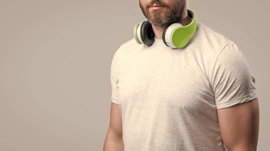 Kulaklıkla müzik dinleyen bir adamın kesilmiş fotoğrafı. Kulaklıkla müzik dinleyen adam gri arka planda izole edilmiş. Adam stüdyoda kulaklıkla müzik dinliyor. Modern kulaklıkla müzik dinleyen bir adam.
