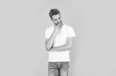 Saç ve sakal bakımı. Kendine güvenen ve yakışıklı, tıraşsız adam. Erkek modası. Erkek güzelliği. Beyaz gömlekli kıllı adam. Sarı arka plandaki neşeli genç adam..