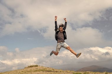 photo of jumping man in a mountain. jumping man outdoor. jumping man in full length. jumping man express happiness.