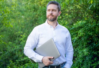 Gururlu iş adamının dışarıda online işi var. İş adamının bilgisayarında internet işi var. İş adamının fotoğrafının internette işi var. İş adamının internet işi var.