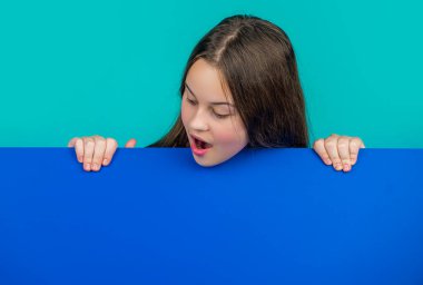 Reklam için fotokopi alanı olan boş mavi kağıdın arkasında büyülenmiş bir çocuk..