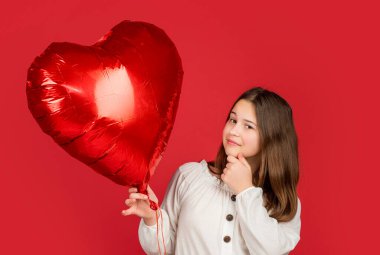 Düşünen çocuk kırmızı arka planda aşk balonu tutuyor..