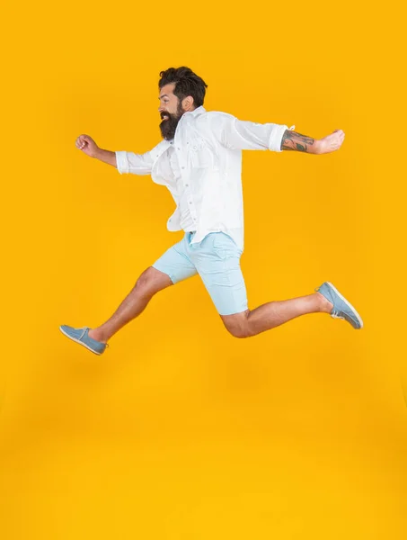 stock image image of happy bearded guy in a hurry wearing summer fashion isolated on yellow background.