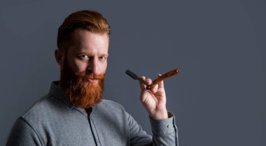 Berber atölyesindeki kızıl saçlı adam. Adam tıraş olmak için berber bıçağı tutuyor. Adam gri arka planda berber bıçağıyla tıraş oluyor. Adam berber dükkanında bıçakla tıraş oluyor..