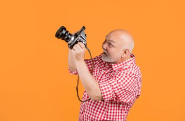 Mutlu gülümseyen yaşlı bir adam sarı bankta eski fotoğraf makinesiyle..