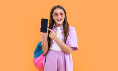 Liseli kız başvuru formunu işaret ediyor. Genç kız öğrenci fotoğrafı. Telefonda başvuru formu. Genç liseli kız sarı renkte izole edilmiş. Genç kız gösteri başvurusu
