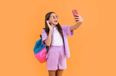 amazed teen selfie school girl on background. photo of teen selfie school girl with phone. teen selfie school girl isolated on yellow. teen selfie school girl in studio.