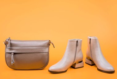 stylish leather boots and hat on yellow background with copy space, accessories.