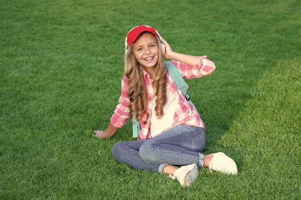 幸せな女の子生徒音楽に耳を傾けます緑の芝生の上に座って屋外で — ストック写真