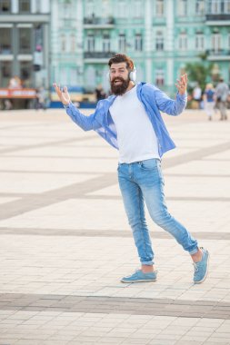 Müzik kulaklıklı hippi adam dışarıda yürüyor. Sokaktaki müzik kulaklıklı hippi adam. Müzik kulaklığı takan hippi bir adamın fotoğrafı. Açık havada müzik kulaklıklı bir hippi..