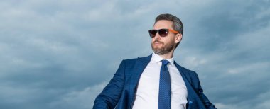 Gökyüzü arka planında fotokopi alanı olan takım elbiseli bir iş adamı. Takım elbiseli iş adamı. Takım elbiseli iş adamı. Takım elbiseli iş adamının fotoğrafı..