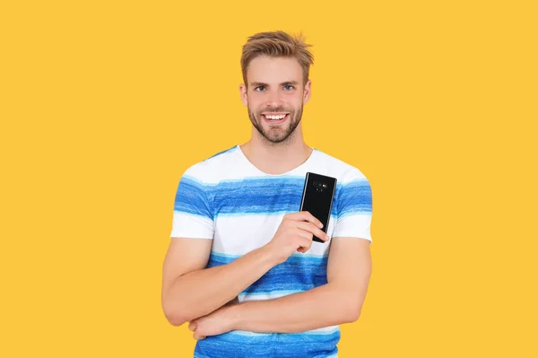 Sorridente Milenar Homem Segurando Telefone Estúdio Isolado Fundo Amarelo — Fotografia de Stock