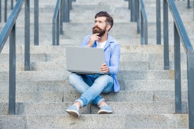 Düşünen adamın dışarıda online video iletişimi var. Adamın dışarıda çevrimiçi video bağlantısı var. Adamın merdivenlerde online video bağlantısı var. Adamın dizüstü bilgisayarında video bağlantısı var..