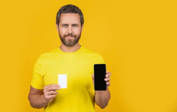 Człowiek Pokazuje Smartfona Karty Izolowane Żółtym Przestrzeń Kopiowania Mężczyzna Pokazuje — Zdjęcie stockowe