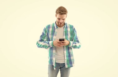 Kareli gömlek giyen bir adam telefonda mesajlaşıyor. Telefonla mesajlaşan adamın fotoğrafı. Telefondaki mesajlaşan adam beyaz arka planda izole edilmiş. Stüdyoda telefonla mesajlaşan sıradan bir adam..