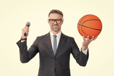 Takım elbiseli olgun bir adamın basketbol topu ve mikrofonu beyaz arka planda tutmasına sevindim..