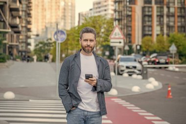 Yetişkin bir adam telefonda konuşuyor. Telefonda el ele konuşan bir adamın fotoğrafı. Adam dışarıda telefonla sohbet ediyor. Adam sokakta telefonla konuşuyor..