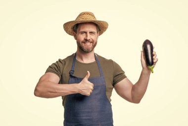 Önlüklü, şapkalı, patlıcan sebzeli, beyaz tenli bir adam. başparmak yukarı.