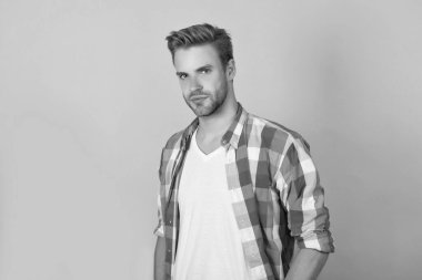 Yakışıklı görünüşüm benim malım. Yakışıklı bir erkek portresi. Genç adam sarı arka planda. Ciddi adam. Kareli tişörtlü havalı çocuk. Erkek yetişkin.