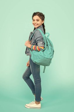 Happy teen girl holding school bag blue background. School education. Back to school.