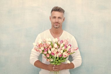 cheerful man with valentines tulips. man with valentines tulips in studio. man with valentines tulips isolated on blue background. photo of man with valentines tulips.