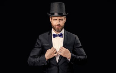 Stüdyoda beyaz smokin şovmeni. Silindir şapkalı smokin şovmeni. Smokin şovmeninin silindir şapkalı fotoğrafı. Smokin şovmeni siyah arka planda izole edilmiş..