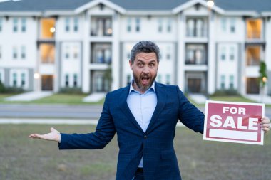 Şok olmuş borsacı satılık mallar için pano tutuyor. Broker Outdoor tarafından satılan bir mülk. Satılık broker 'ın fotoğrafı. Simsar tarafından satılan mal.