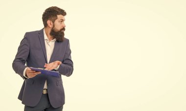 Puzzled businessman pointing at clipboard. Businessman doing work checklist studio. Businessman working with documents. Professional man ingaged in paperwork isolated on white, copy space.