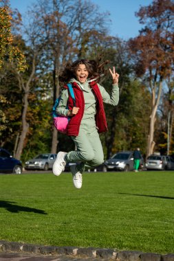 liseli kız dışarıda zıplıyor. Sırt çantalı liseli kız. Parktaki genç kızın fotoğrafı. Okullu genç kız..