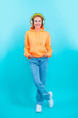 Stüdyoda neşeli bir milenyum kadını. Arkaplanda bin yıllık bir kadın. Milenyum kadınının fotoğrafı. Müzik dinle. Milenyum kadını maviden izole edilmiş..