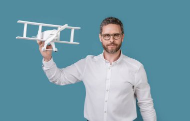 Stüdyoda bir adamın hayalleri, hayattaki hedefleri. Adam uçakla hedefleri fırlatıyor. İnsanoğlunun oyuncak uçakla heveslerini fırlatma fotoğrafı. adam başlatma özlemleri mavi arkaplanda izole.