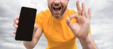 Akıllı telefon ekranı ile fotokopi alanı sunan adamın kırpılmış görüntüsü. Tamam.