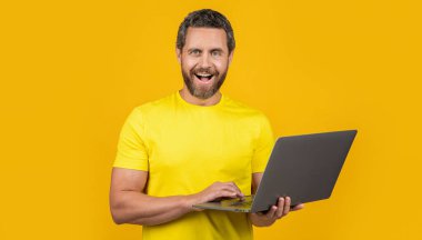Stüdyodaki mutlu adam programcısı. Dizüstü bilgisayarlı insan programcısının fotoğrafı. İnsan programcısı sarıda izole edildi. Arka plandaki adam programcısı.