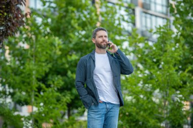 Akıllı telefondan arayan ve konuşan bir adamın görüntüsü. Adamın dışarıda akıllı telefonları var. Sokakta akıllı telefon görüşmesi yapan bir adam. Adam dışarıdaki akıllı telefondan arıyor..