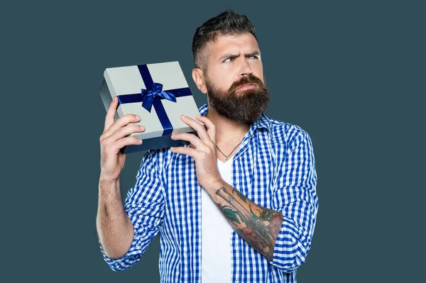 stock image displeased mature bearded guy with present box on grey background.