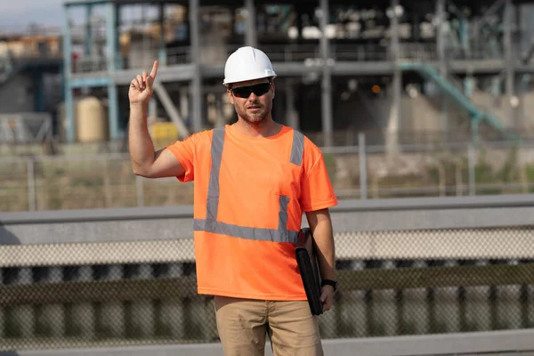 engineer man at construction site with raised finger wearing hardhat. engineer man at construction site outdoor. f engineer man at construction site. engineer man at construction site.