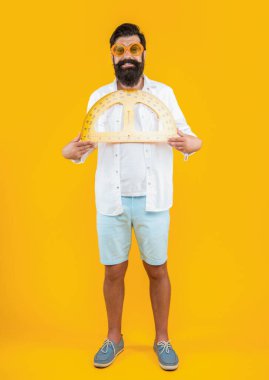 Arka planda geometri açıölçeri olan neşeli bir adam. Geometri açıölçeri olan bir adamın fotoğrafı. Geometri açıölçeri olan adam sarıda izole edilmiş. Stüdyoda geometri açıölçeri olan bir adam.