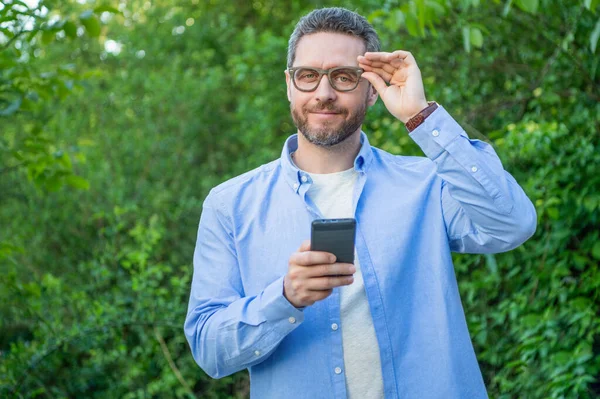 Gülümseyen adam telefonda mesaj atıyor, kopyala uzayı. Adam dışarıda telefonla mesajlaşıyor. Telefonla mesajlaşan ya da e-postaları kontrol eden bir adam. Telefonda mesajlaşan adamın fotoğrafı..