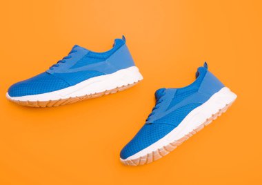 Koşmak için spor ayakkabıları. Bir çift rahat spor ayakkabı. Spor mavi spor ayakkabılar. Sarı arka planda ayakkabılar. Ayakkabı dükkanı. Alışveriş konsepti. Eğitim için ayakkabılar.