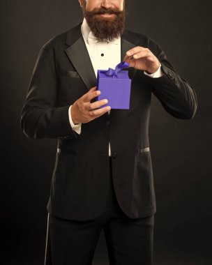 Smokinli neşeli bir adam siyah arka planda siyah papyon takıyor ve kutulu. doğum.