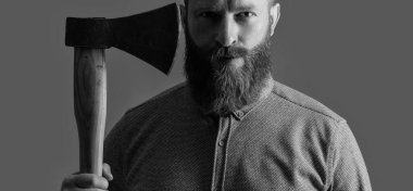 barber concept. man barber with red beard hold axe isolated on grey background. barber man with axe has red beard. studio shot of red beard barber man.