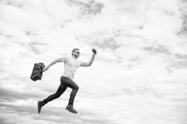 Seyahat çantasıyla çalışan enerjik bir adam gökyüzü arkaplanı, kopyalama alanı.