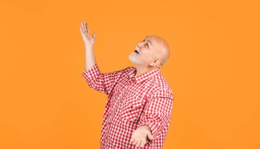 Sarı arka planda kareli gömlekli mutlu yaşlı adam..