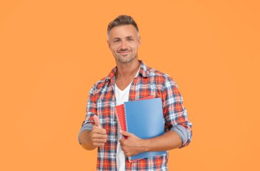 Sıradan takılan mutlu bir adam, elinde okul kitapları, sarı arka plan, eğitim..