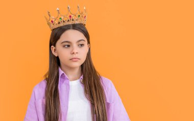 teen selfish girl with crown in studio, copy space. teen selfish girl with crown on background. photo of teen selfish girl with crown. teen selfish girl with crown isolated on yellow.