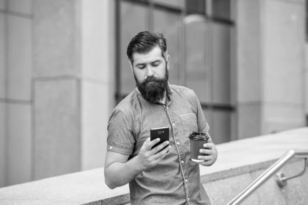 屋外でコーヒーを飲みながら携帯電話でソーシャルメディアをサーフィン髭男 モバイルデバイスでのモバイルインターネットの利用 モバイル通信 — ストック写真