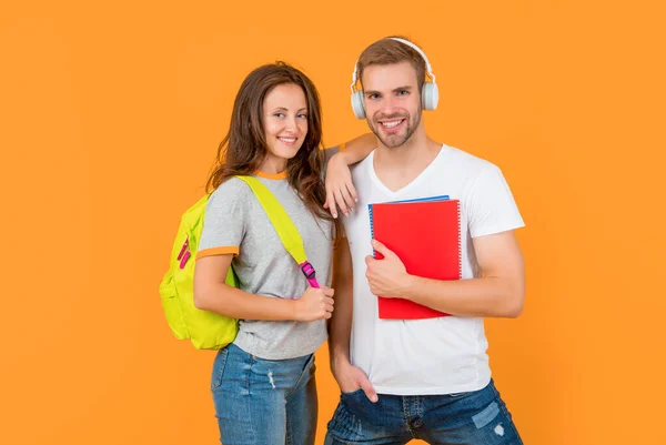 stock image smiling university students in headphones with workbook and backpack on yellow background, music.